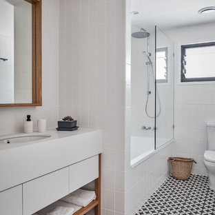 Beach style 3/4 bathroom in Gold Coast - Tweed with flat-panel cabinets, white cabinets, an alcove tub, a shower/bathtub combo, white tile, subway tile, white walls, cement tiles, black floor, white benchtops and an undermount sink.