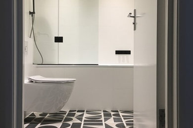 Inspiration for a small modern bathroom in London with flat-panel cabinets, a built-in bath, a shower/bath combination, a wall mounted toilet, black and white tiles, ceramic tiles, white walls, ceramic flooring, a wall-mounted sink and solid surface worktops.