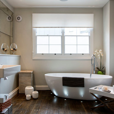 Mid-sized trendy master dark wood floor and brown floor freestanding bathtub photo in London with a wall-mount sink and beige walls