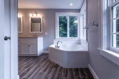 Diseño de cuarto de baño principal minimalista con bañera esquinera, baldosas y/o azulejos blancos, paredes grises, lavabo bajoencimera y suelo gris
