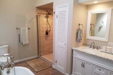 Ejemplo de cuarto de baño clásico de tamaño medio con bañera con patas, baldosas y/o azulejos de mármol, paredes beige y suelo de madera en tonos medios