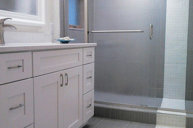 Diseño de cuarto de baño principal moderno de tamaño medio con lavabo bajoencimera, armarios estilo shaker, puertas de armario blancas, encimera de cuarzo compacto, baldosas y/o azulejos grises, baldosas y/o azulejos de porcelana y suelo de baldosas de porcelana