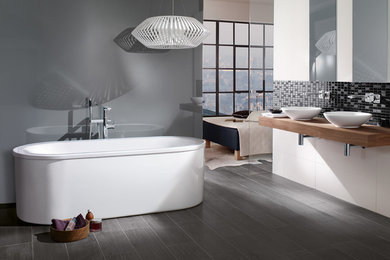 ニューヨークにあるトランジショナルスタイルのおしゃれな浴室 (ベッセル式洗面器、置き型浴槽、グレーの壁) の写真