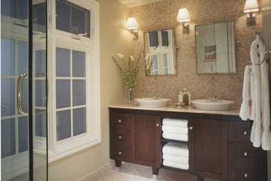 Mid-sized transitional master limestone floor and beige floor alcove shower photo in Los Angeles with shaker cabinets, dark wood cabinets, beige walls, a vessel sink and a hinged shower door