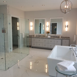Modelo de cuarto de baño principal, moderno, grande, con armarios con paneles lisos, puertas de armario blancas, bañera exenta, ducha a ras de suelo, sanitario de una pieza, baldosas y/o azulejos blancos, baldosas y/o azulejos de piedra, paredes blancas, suelo de mármol, lavabo bajoencimera, encimera de cuarzo compacto, suelo blanco y ducha con puerta con bisagras