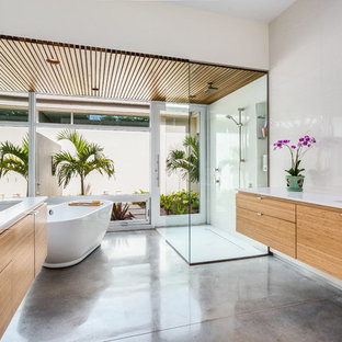 Inspiration för exotiska en-suite badrum, med ett undermonterad handfat, släta luckor, skåp i mellenmörkt trä, bänkskiva i kvarts, ett fristående badkar, en kantlös dusch, vit kakel, betonggolv, beige väggar och grått golv