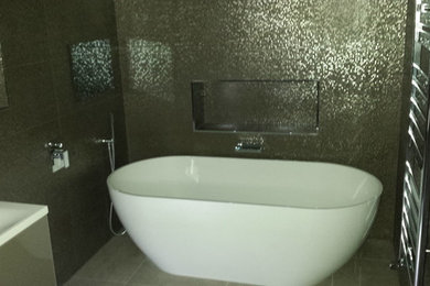 Medium sized contemporary ensuite bathroom in Essex with a freestanding bath, a wall mounted toilet, brown tiles, mosaic tiles, porcelain flooring and a wall-mounted sink.