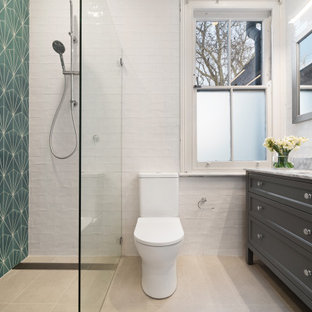 This is an example of a transitional 3/4 bathroom in Sydney with recessed-panel cabinets, grey cabinets, a curbless shower, a two-piece toilet, green tile, white tile, subway tile, an undermount sink, marble benchtops, beige floor and grey benchtops.