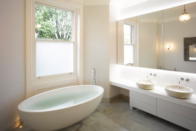 Contemporary family bathroom in London with flat-panel cabinets, white cabinets, a freestanding bath, porcelain flooring, a vessel sink, marble worktops, grey worktops, double sinks and a built in vanity unit.