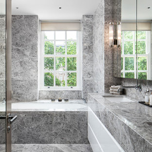 Contemporary bathroom in Surrey with flat-panel cabinets, white cabinets, a submerged bath, a submerged sink, grey floors and grey worktops.