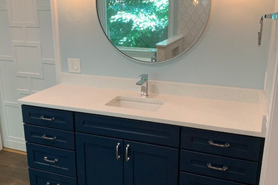 Example of a large arts and crafts master dark wood floor and brown floor bathroom design in Atlanta with recessed-panel cabinets, blue cabinets, blue walls, an undermount sink, quartz countertops and white countertops