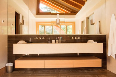 This is an example of a large contemporary ensuite bathroom in Vancouver with a wall-mounted sink, freestanding cabinets, light wood cabinets and ceramic flooring.