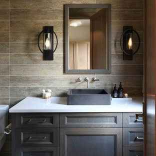 Mountain style brown tile white floor bathroom photo in Other with recessed-panel cabinets, dark wood cabinets, brown walls, a vessel sink and white countertops
