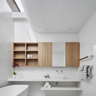 Design ideas for a mid-sized contemporary bathroom in Melbourne with open cabinets, a freestanding tub, white tile, glass tile, mosaic tile floors, a vessel sink, solid surface benchtops, white benchtops, light wood cabinets, white walls and white floor.