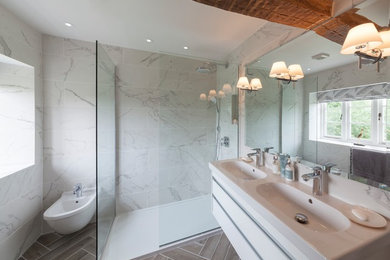 Inredning av ett lantligt mellanstort en-suite badrum, med en öppen dusch, vit kakel, vita väggar, klinkergolv i porslin, ett konsol handfat, grått golv, med dusch som är öppen, släta luckor, vita skåp och en bidé