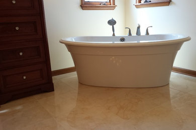 Modelo de cuarto de baño principal tradicional de tamaño medio con bañera exenta, paredes blancas, suelo de baldosas de cerámica y suelo beige