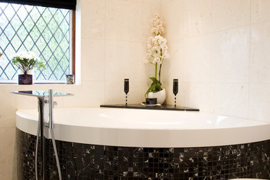 Small contemporary family bathroom in Sussex with a corner bath, black and white tiles, mosaic tiles, pebble tile flooring, a shower/bath combination and beige walls.