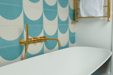 ロンドンにある小さな地中海スタイルのおしゃれなマスターバスルーム (オープンシェルフ、白いキャビネット、人工大理石カウンター、置き型浴槽、壁掛け式トイレ、青いタイル、磁器タイル、白い壁、磁器タイルの床、ベッセル式洗面器、青い床、白い洗面カウンター) の写真
