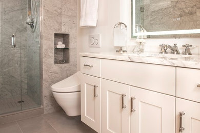 Example of a small transitional master gray tile and marble tile porcelain tile and gray floor alcove shower design in Seattle with shaker cabinets, white cabinets, a wall-mount toilet, white walls, an undermount sink, marble countertops and a hinged shower door