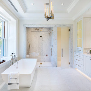 Example of a transitional master gray tile and marble tile mosaic tile floor, white floor, double-sink and tray ceiling bathroom design in Boston with recessed-panel cabinets, white cabinets, a bidet, white walls, an undermount sink, marble countertops, a hinged shower door, gray countertops and a built-in vanity