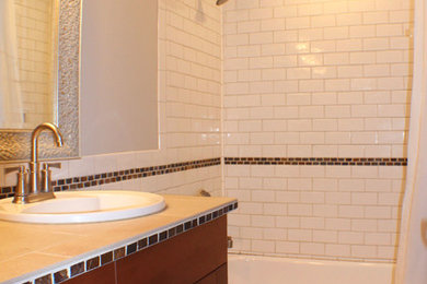 Modelo de cuarto de baño tradicional renovado de tamaño medio con suelo con mosaicos de baldosas, paredes beige, bañera empotrada, combinación de ducha y bañera, lavabo encastrado, armarios estilo shaker, puertas de armario de madera oscura y aseo y ducha