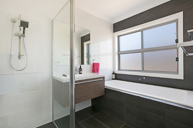 Modelo de cuarto de baño principal actual de tamaño medio con bañera esquinera, ducha abierta y lavabo suspendido