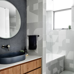 Inspiration for a mid-sized scandinavian bathroom in Sydney with medium wood cabinets, a drop-in tub, a shower/bathtub combo, blue tile, porcelain tile, porcelain floors, a vessel sink, engineered quartz benchtops and grey floor.