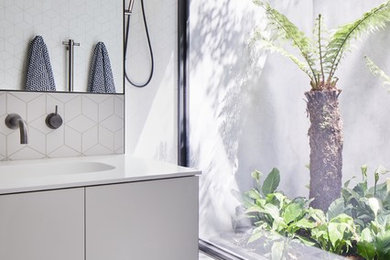 Modelo de cuarto de baño contemporáneo con armarios con paneles lisos, puertas de armario grises, baldosas y/o azulejos blancos, lavabo integrado, suelo gris y encimeras blancas