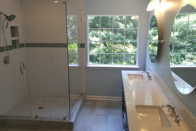 Example of a large trendy master gray tile and ceramic tile corner shower design in DC Metro with furniture-like cabinets, dark wood cabinets, a two-piece toilet, blue walls, an undermount sink and quartz countertops