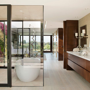 Ispirazione per un'ampia stanza da bagno padronale design con ante lisce, ante in legno bruno, vasca freestanding, piastrelle beige, piastrelle in pietra, pareti marroni, parquet chiaro, lavabo sottopiano e top in marmo