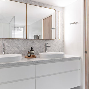This is an example of a contemporary bathroom in Sydney with flat-panel cabinets, white cabinets, white tile, white walls, a vessel sink, grey floor, white benchtops, a double vanity and a floating vanity.