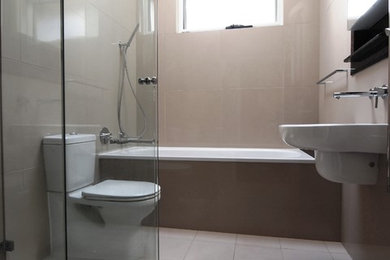 Esempio di una stanza da bagno padronale moderna di medie dimensioni con lavabo sospeso, vasca da incasso, doccia ad angolo, WC sospeso, piastrelle beige, piastrelle in gres porcellanato, pareti beige e pavimento in gres porcellanato