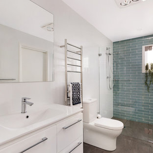 Design ideas for a mid-sized contemporary bathroom in Sydney with white cabinets, an alcove shower, a two-piece toilet, multi-coloured tile, white walls, an integrated sink, engineered quartz benchtops, brown floor, a hinged shower door and white benchtops.