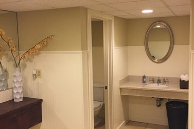 This is an example of a medium sized traditional bathroom in New York with a two-piece toilet, beige tiles, green walls, porcelain flooring, a submerged sink and laminate worktops.