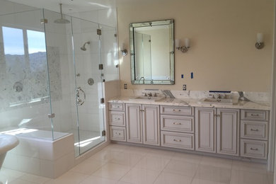 Example of a large minimalist master white tile marble floor bathroom design in San Francisco with raised-panel cabinets, white cabinets, a one-piece toilet, beige walls, a drop-in sink and marble countertops