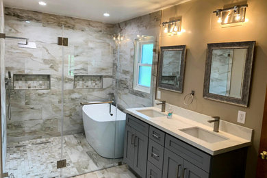Large transitional master beige tile and marble tile marble floor, beige floor and double-sink bathroom photo in Los Angeles with recessed-panel cabinets, gray cabinets, beige walls, marble countertops, a hinged shower door, white countertops and a built-in vanity