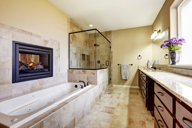 Inspiration for a large classic ensuite bathroom in Los Angeles with flat-panel cabinets, dark wood cabinets, a built-in bath, a corner shower, a wall mounted toilet, beige tiles, stone tiles, beige walls, ceramic flooring, a submerged sink, granite worktops, beige floors and a hinged door.