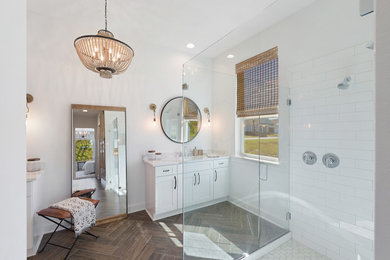 Double shower - large industrial master white tile and ceramic tile porcelain tile and brown floor double shower idea in Jacksonville with shaker cabinets, white cabinets, a two-piece toilet, white walls, an undermount sink, quartz countertops, a hinged shower door and white countertops
