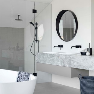 Inspiration for a large contemporary master bathroom in Sydney with flat-panel cabinets, grey cabinets, a freestanding tub, a double shower, a one-piece toilet, white tile, ceramic tile, white walls, ceramic floors, a drop-in sink, marble benchtops, grey floor, a hinged shower door and grey benchtops.