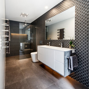 Expansive contemporary 3/4 bathroom in Sydney with flat-panel cabinets, white cabinets, a curbless shower, a one-piece toilet, black tile, an integrated sink, brown floor, an open shower, white benchtops, porcelain tile, brown walls, porcelain floors and solid surface benchtops.