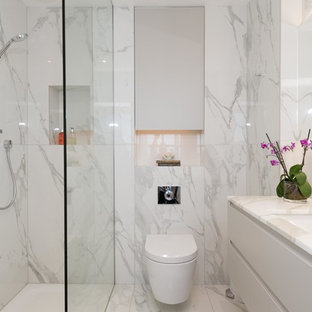 Inspiration for a medium sized contemporary shower room bathroom in London with flat-panel cabinets, white cabinets, a shower/bath combination, a wall mounted toilet, marble tiles, marble flooring, white floors, white tiles, a submerged sink, marble worktops and an open shower.