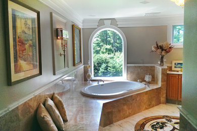 Inspiration for a huge mediterranean master brown tile and ceramic tile marble floor corner bathtub remodel in Boston with a drop-in sink, raised-panel cabinets, medium tone wood cabinets, limestone countertops and green walls