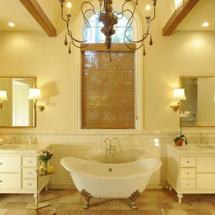 Esempio di una stanza da bagno padronale chic di medie dimensioni con vasca con piedi a zampa di leone, piastrelle beige, pareti beige, ante con riquadro incassato, ante bianche, piastrelle diamantate, pavimento in pietra calcarea, lavabo sottopiano e top in marmo