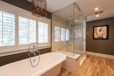 Photo of a medium sized modern ensuite bathroom in New York with a freestanding bath, a corner shower, marble tiles, brown walls, medium hardwood flooring and a hinged door.