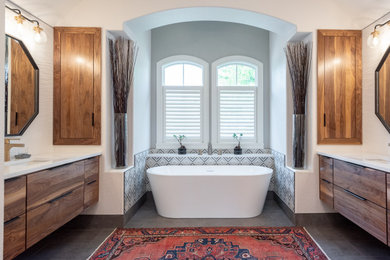 Photo of a medium sized traditional ensuite bathroom in Indianapolis with flat-panel cabinets, medium wood cabinets, a freestanding bath, a corner shower, white tiles, porcelain tiles, white walls, ceramic flooring, a submerged sink, engineered stone worktops, grey floors, an open shower, white worktops, a wall niche, double sinks and a floating vanity unit.