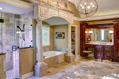 Large tuscan master beige tile and mosaic tile travertine floor alcove bathtub photo in Kansas City with raised-panel cabinets, dark wood cabinets, beige walls, a pedestal sink and granite countertops