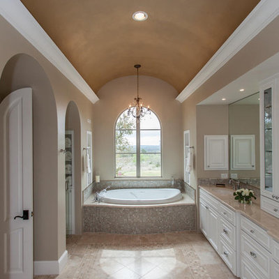 Elegant beige tile and mosaic tile drop-in bathtub photo in Austin with white cabinets