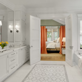 Foto de cuarto de baño principal, clásico, grande, con puertas de armario blancas, bañera encastrada sin remate, baldosas y/o azulejos blancos, paredes blancas, suelo de mármol, lavabo bajoencimera, encimera de mármol, armarios con paneles empotrados, losas de piedra, suelo blanco y encimeras blancas