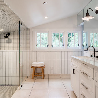 Example of a large transitional master white tile and ceramic tile limestone floor, beige floor, double-sink and vaulted ceiling bathroom design in Other with shaker cabinets, white cabinets, white walls, an undermount sink, marble countertops, white countertops and a built-in vanity