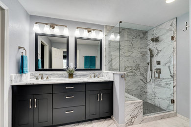Corner shower - transitional master porcelain tile and gray floor corner shower idea in Denver with shaker cabinets, brown cabinets, gray walls, an undermount sink, marble countertops, a hinged shower door and white countertops